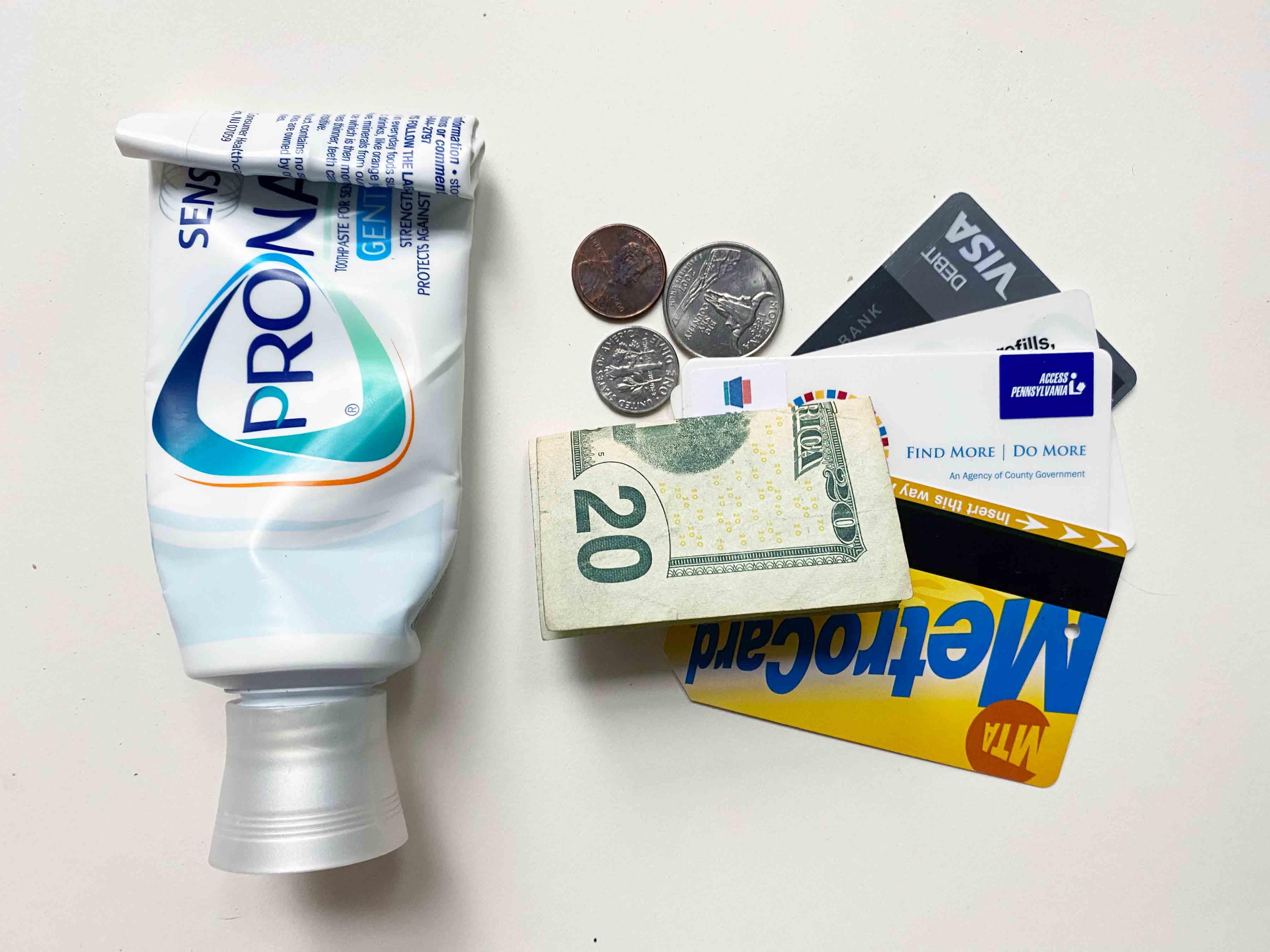 toothpaste tube rolled up with cash and credit cards next to it