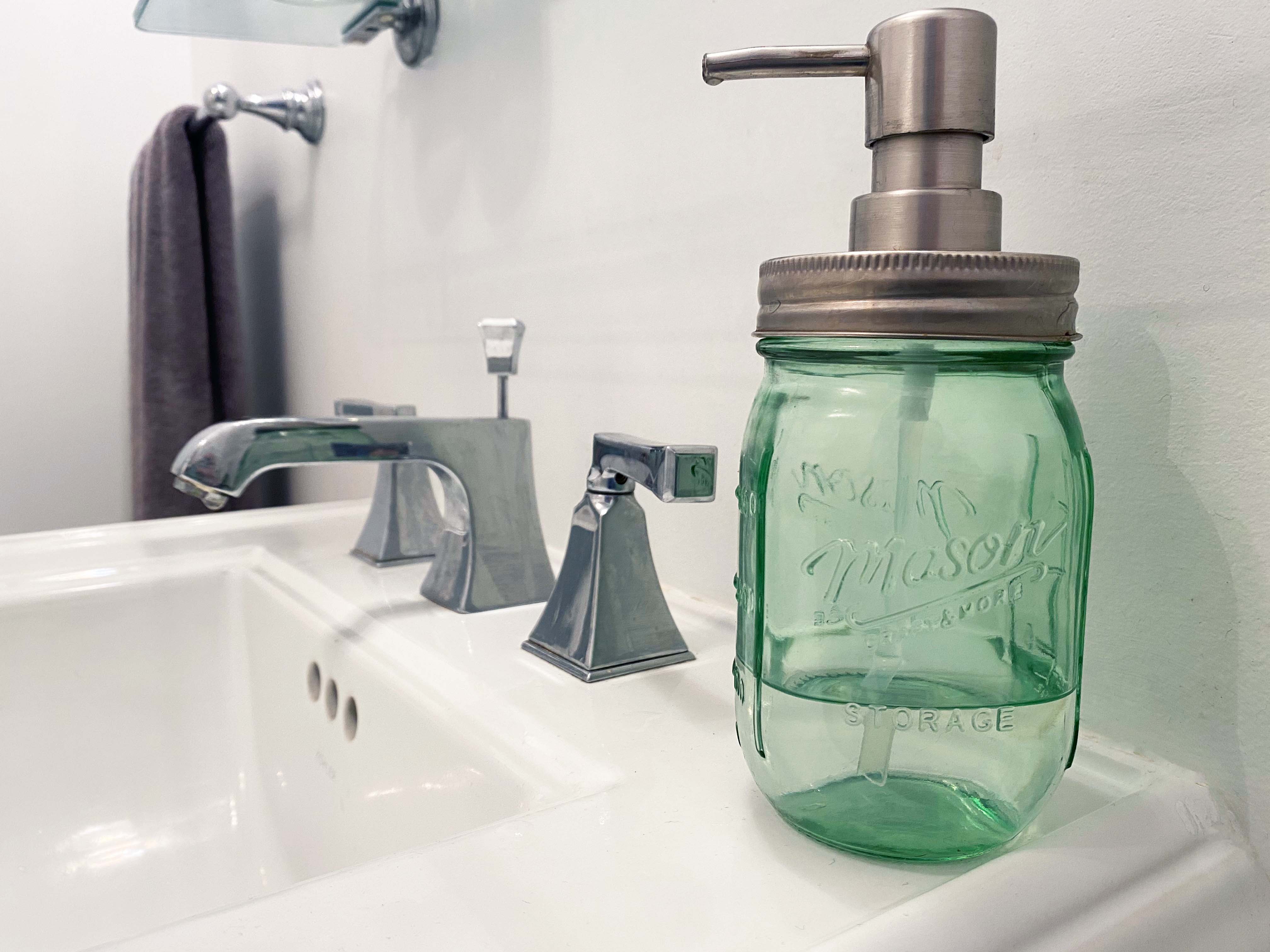 hand getting soap from dispenser over sink