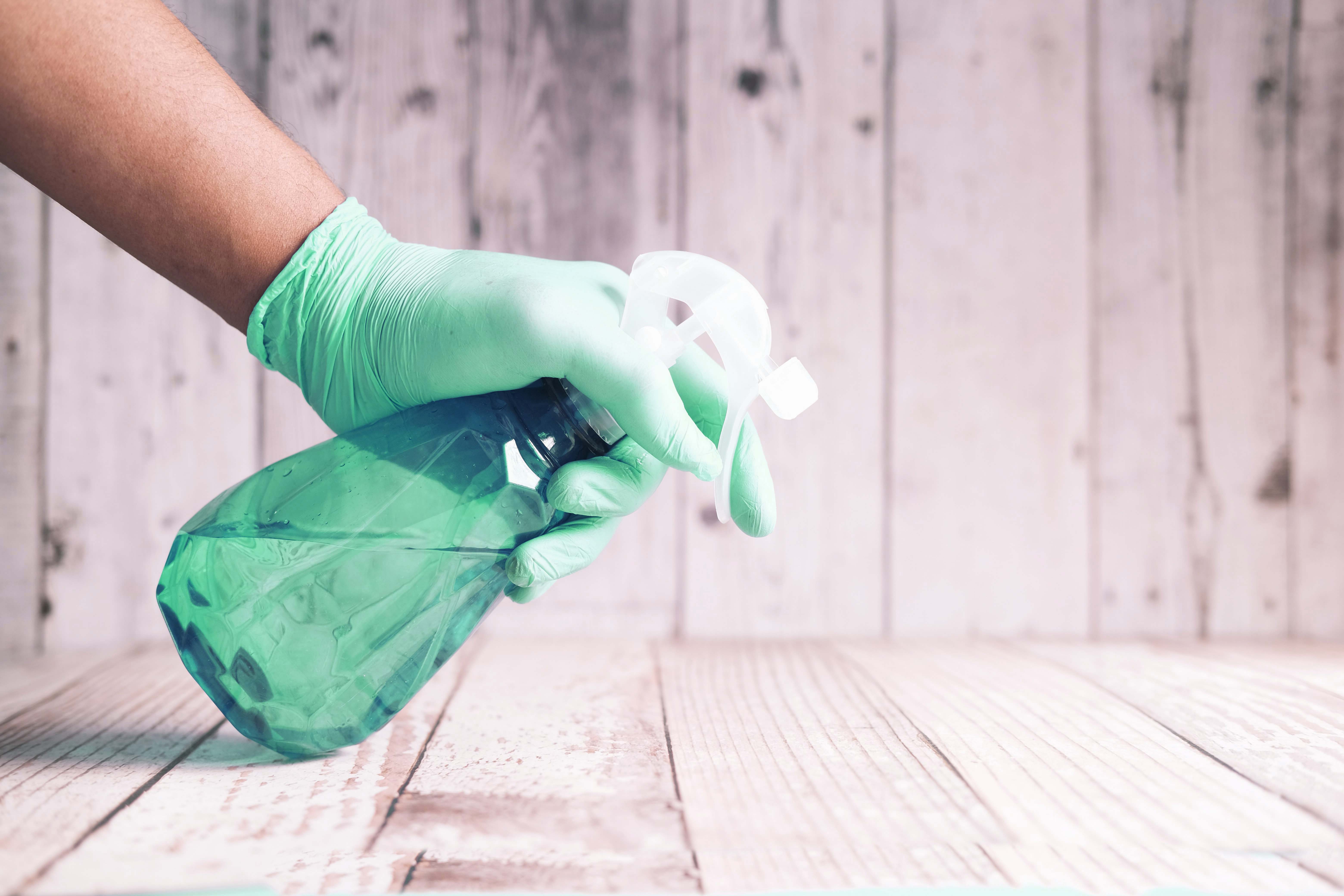 hand wearing glove and spraying liquid from spray bottle