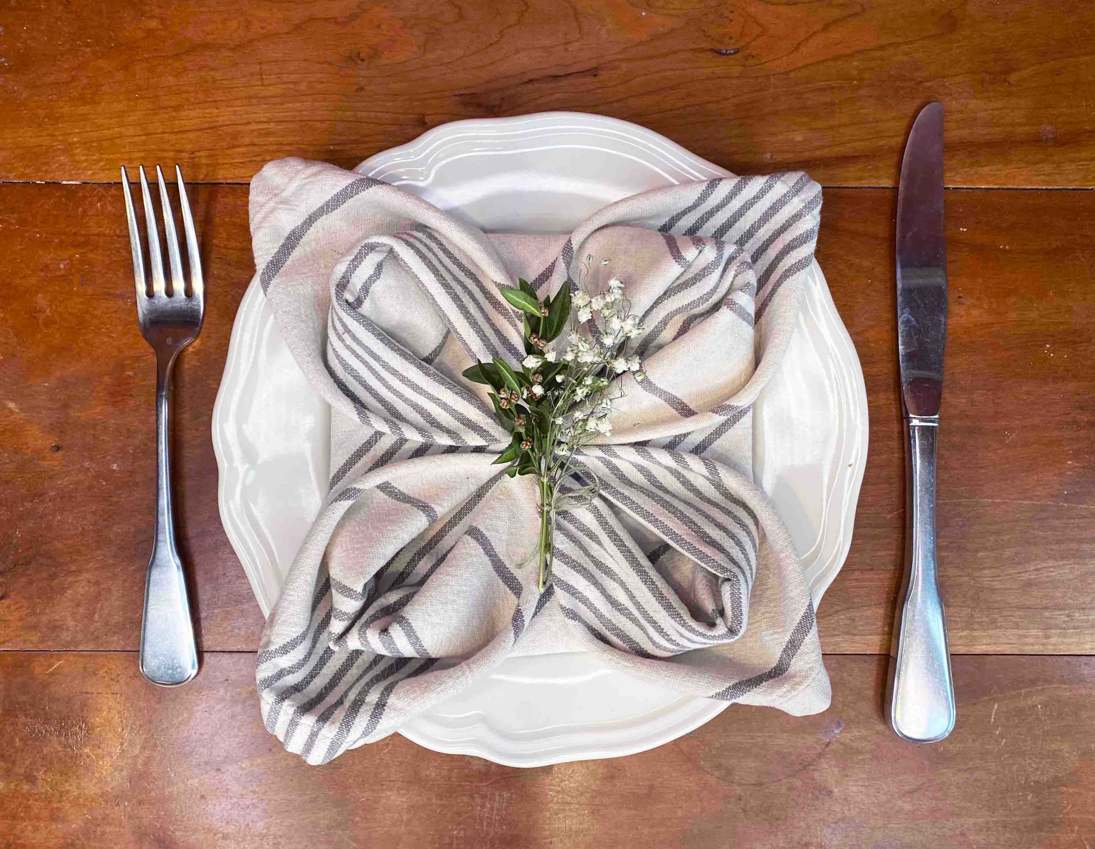 Napkin folded like flower on plate with fork and knife set on either side