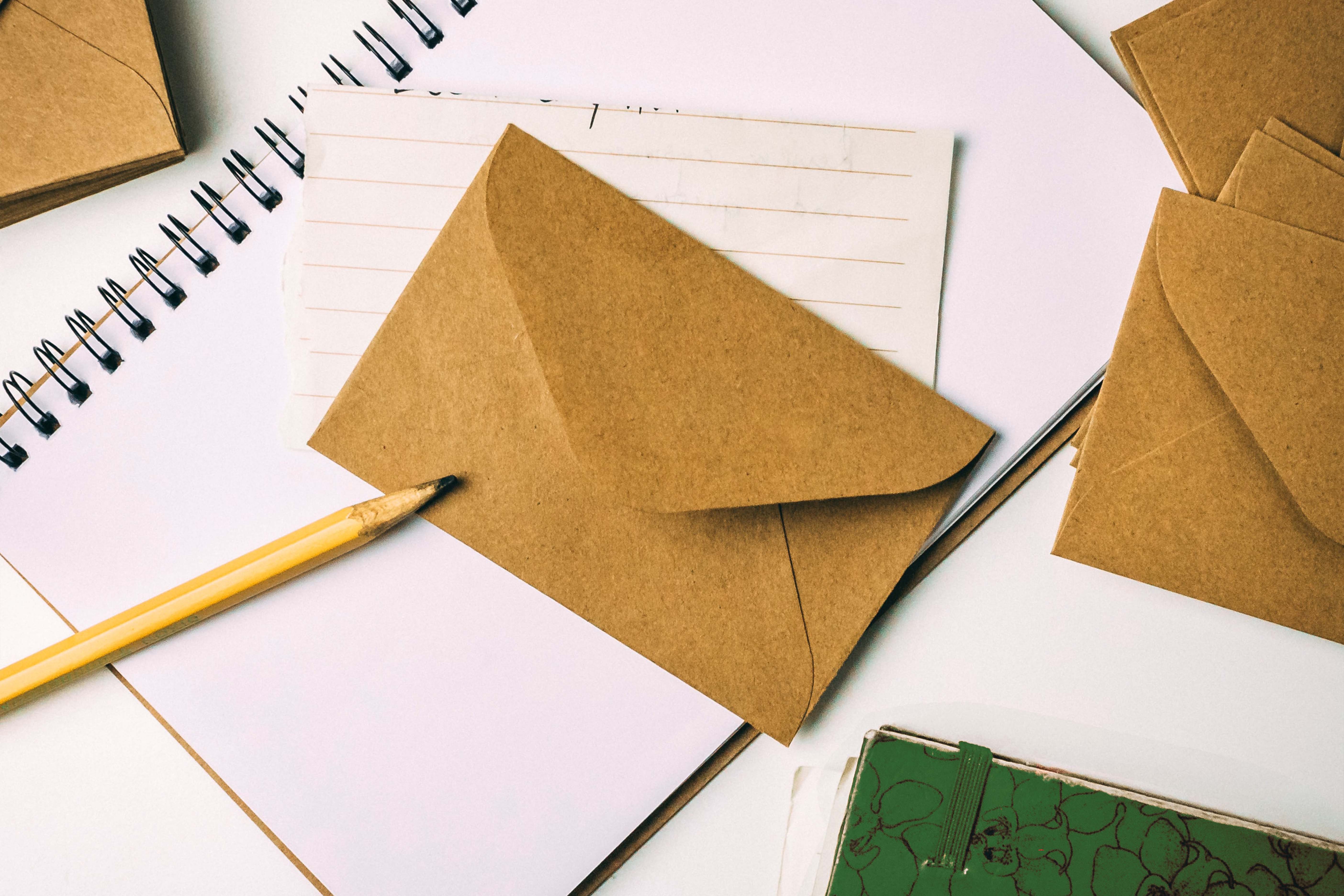 pencil and envelopes on spiral notebook